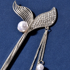 Detail of silver mermaid tail hair stick with sparkling rhinestones and white pearls