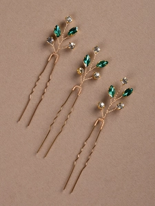 Vue détaillée de trois épingles à cheveux de mariée dorées en U avec cristaux verts et clairs