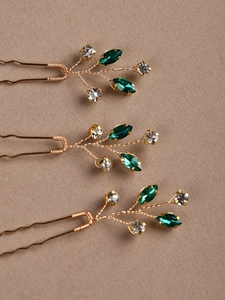Détail de trois épingles à cheveux de mariée en fil d'or avec cristaux émeraude et zircons