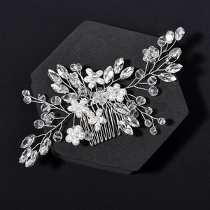 Macro detail of bridal hair comb featuring pearls and crystals on a dark stand