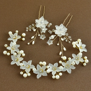 Dettaglio accessori capelli sposa con fiori bianchi, perle e filo dorato a mano