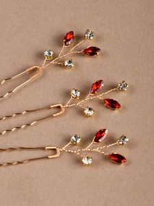 Détail de trois épingles à cheveux de mariée avec branches dorées et pierres rouges
