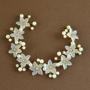 Dettaglio dell'accessorio capelli con fiori bianchi opachi, perle e filo dorato