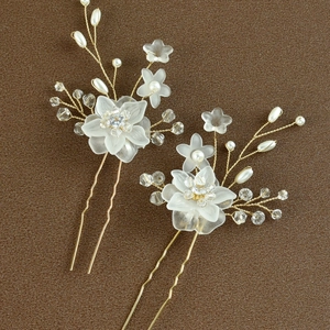 Dettaglio di due forcine dorate fatte a mano con petali bianchi e perle di cristallo