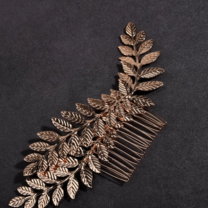 Macro detail of golden metal hair comb featuring three leaves with intricate vein texture