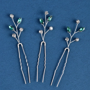 Détail de trois épingles à cheveux de mariée argentées avec strass verts et blancs