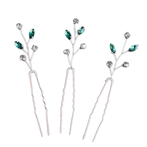 Détail de trois épingles à cheveux de mariée avec strass vert émeraude et motif de feuilles
