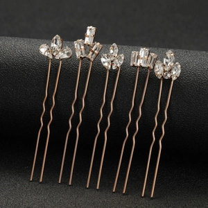 Five rose gold bridal hair pins with marquise crystal rhinestones on black background