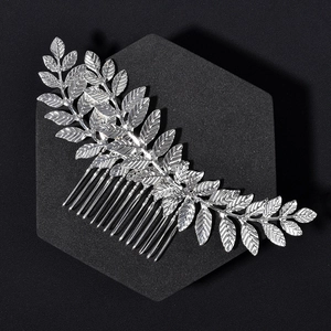 Macro detail of silver leaf hair comb with ten metal teeth on a black display stand