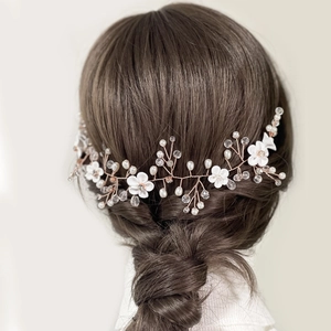 Détail d'une vigne de cheveux de mariée avec fleurs en céramique blanche et perles en cristal
