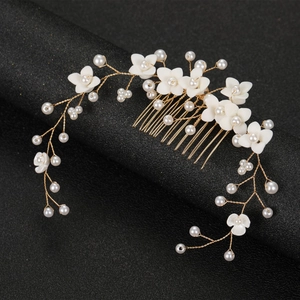 Détail de fleurs en céramique blanche et perles sur un peigne de mariée doré fait main