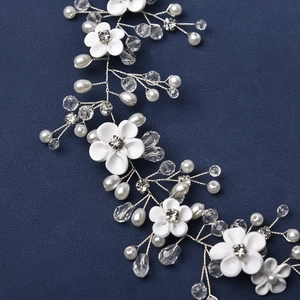 Détail d'un accessoire de cheveux de mariée avec fleurs en résine et perles blanches