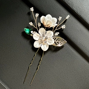 Détail de fleurs en soie blanche et pierres marquises vertes sur une épingle à cheveux de mariée