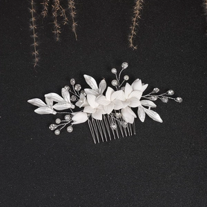 Bridal hair comb featuring white ceramic flowers, silver leaves, pearls, and rhinestones
