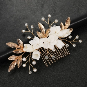 Detailed view of white ceramic flowers and golden alloy leaf hair comb for weddings