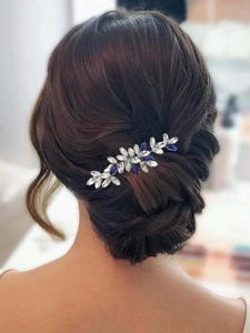Gros plan d'un peigne à cheveux de mariée en cristal bleu roi sur un chignon foncé élégant