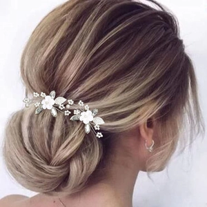 Détail de fleurs en argile blanche et perles sur épingles à cheveux de mariée en chignon