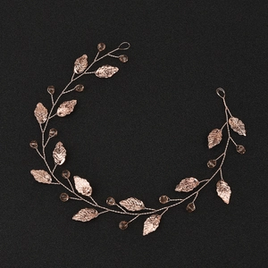 Handmade rose gold leaf bridal hair vine with crystal beads on a textured black background