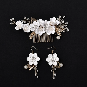 Detail of bridal hair comb and earrings set with white handmade flowers and gold leaves