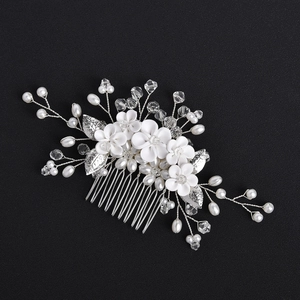 Close-up of bridal hair comb with white resin flowers, pearls and crystals on silver metal