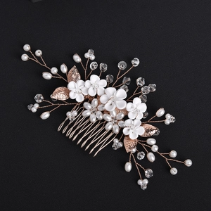 Detailed close-up of handmade bridal hair comb with white flowers and rose gold leaves