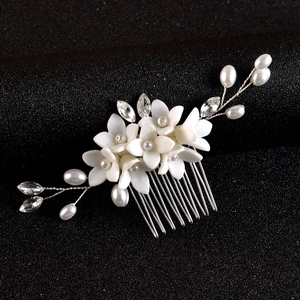 Close-up of white ceramic flower bridal hair comb with pearls and silver wire detail