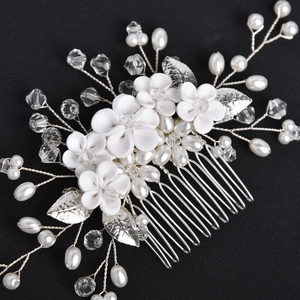 Detail of white handmade clay flowers with silver metal leaves and pearls for wedding hair comb