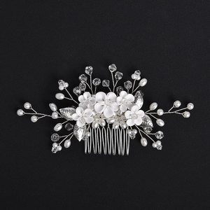 Detail of bridal hair comb with white fabric flowers, silver leaves, and faux pearls
