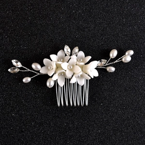 Close-up of handmade bridal hair comb with white ceramic flowers and silver beads