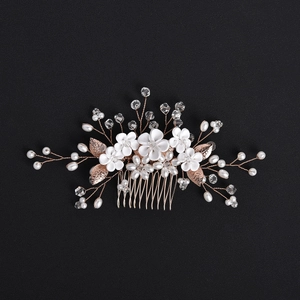 Detail of white ceramic flowers and gold leaves bridal hair comb with pearls and crystals