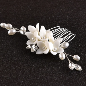 Detailed close-up of handmade white ceramic flowers and pearls on a bridal hair comb