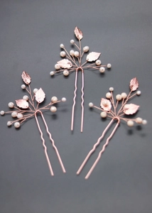 Detail of rose gold hair pins set with white pearls and textured metal leaf elements