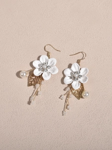 Detail of bridal earrings featuring white fabric flowers with rhinestones and pearl tassels
