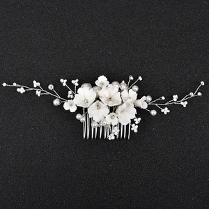 Détail macro du peigne de mariée avec fleur en céramique blanche et perles
