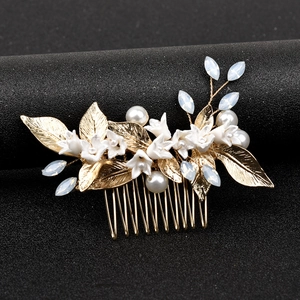 Detail of bridal hair comb with white ceramic flowers, gold leaves and pearls