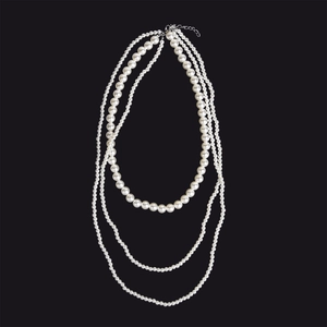 Detail einer dreilagigen weißen Perlenkette mit eleganten Schichten und Metallverschluss