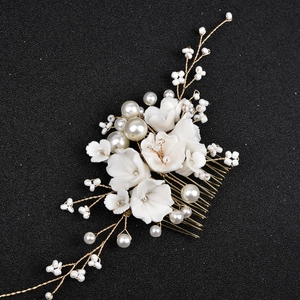 Détail de fleurs en céramique blanche et perles de mariée sur peigne à cheveux doré