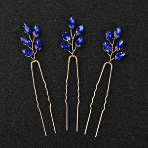 Dettaglio di tre forcine dorate con pietre preziose in vetro blu a forma di foglia