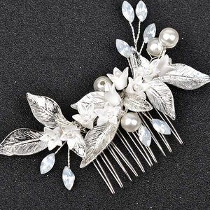 Elegant bridal hair comb with white ceramic flowers, silver leaves, and pearls on black back