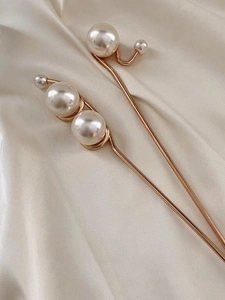 Gros plan détaillé d'épingles à cheveux en perles dorées sur soie de couleur champagne