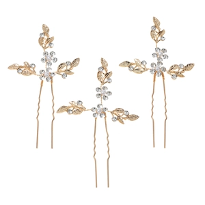 Close-up of three gold leaf bridal hair pins with clear rhinestones and white pearls