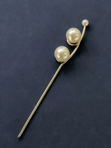 Gros plan détaillé d'une épingle à cheveux dorée avec trois perles en dégradé