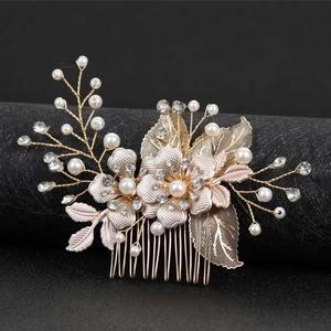Golden bridal hair comb with resin petals, pearls and hollow leaf design on dark pedestal