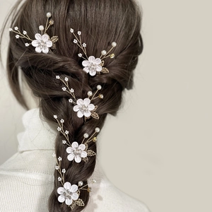 Five-piece bridal hair pin set with white flowers, pearls and crystals in braided hair