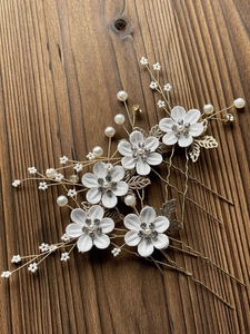 Detail of 5-piece bridal hair pin set with white flowers, gold leaves and crystals