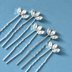 Detail of five silver U-shaped hair pins with sparkling crystal leaf decorative tops