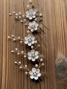 Detail of 5-piece bridal hair pin set with white fabric flowers and golden rhinestones