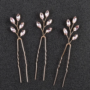 Dettaglio di tre forcine per capelli dorate con pietre di cristallo rosa su nero