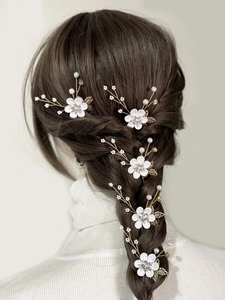 Detail of 5-piece floral bridal hair pins with pearls and gold leaves on braided hair