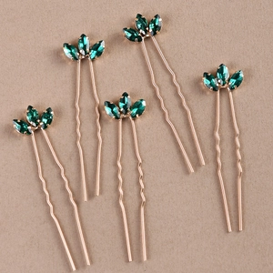 Detail view of five U-shaped gold metal hair pins with green marquise rhinestone petals